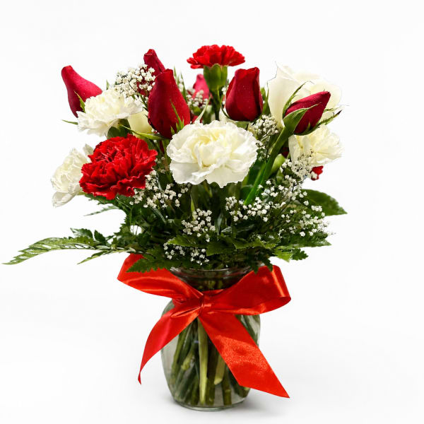 Red and white flowers in a glass vase with a red ribbon