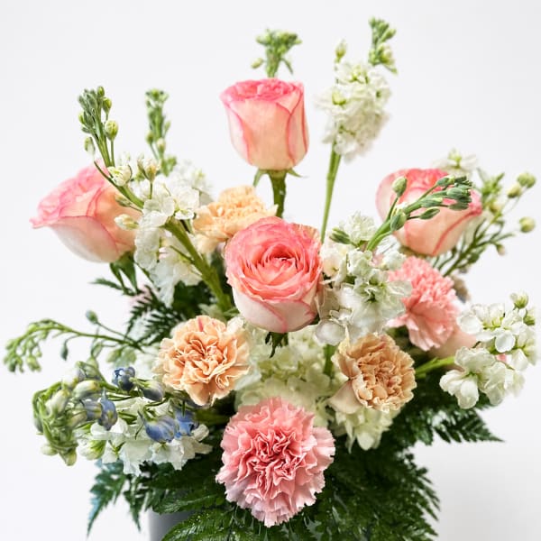 Pink roses and carnations arranged with white flowers in a vase