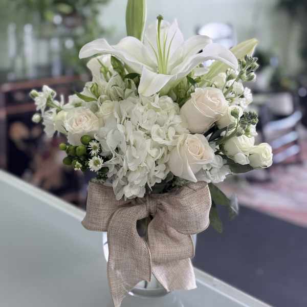 White lily and rose bouquet with hydrangea in a glass vase