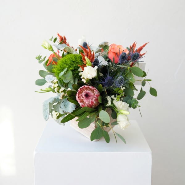 Mixed bouquet with coral and white blooms in a white container