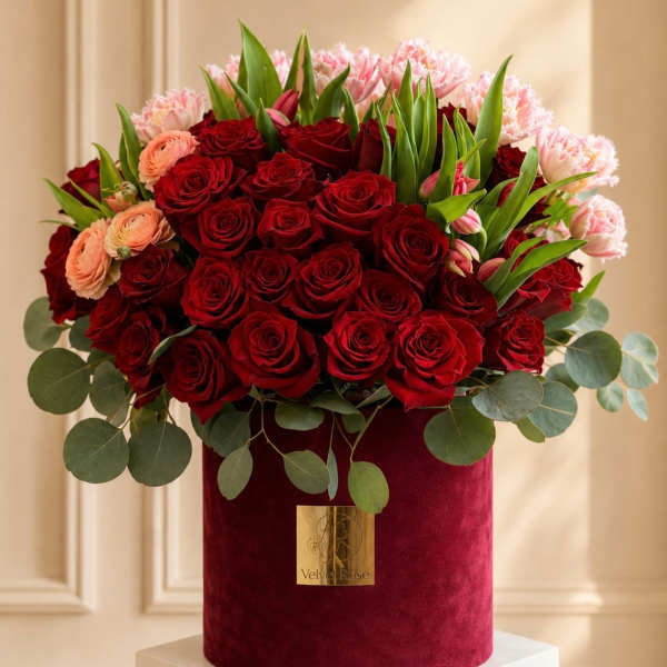 Red roses and pink flowers arranged in a velvet hat box