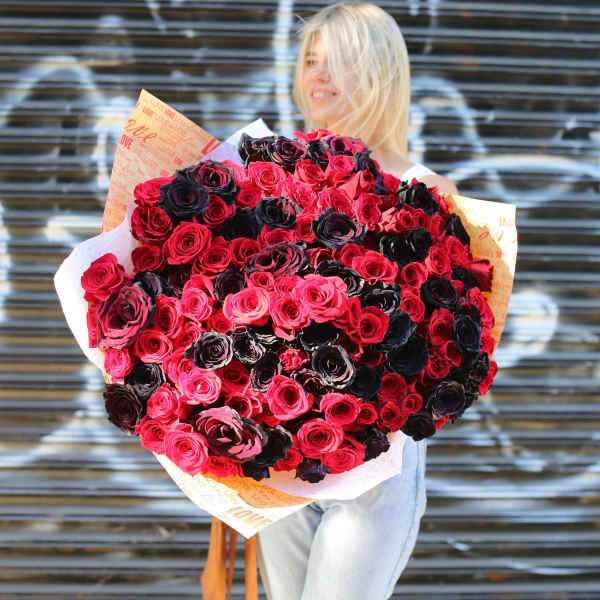Large bouquet of red, pink, and dark roses wrapped in printed paper