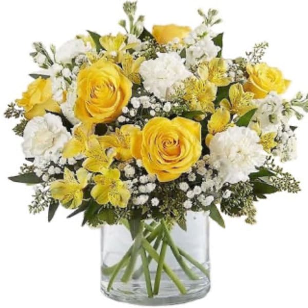Yellow roses and white flowers in a clear glass vase