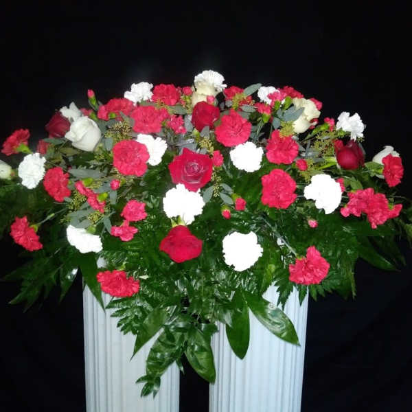 Large red, white, and pink floral arrangement in a white container