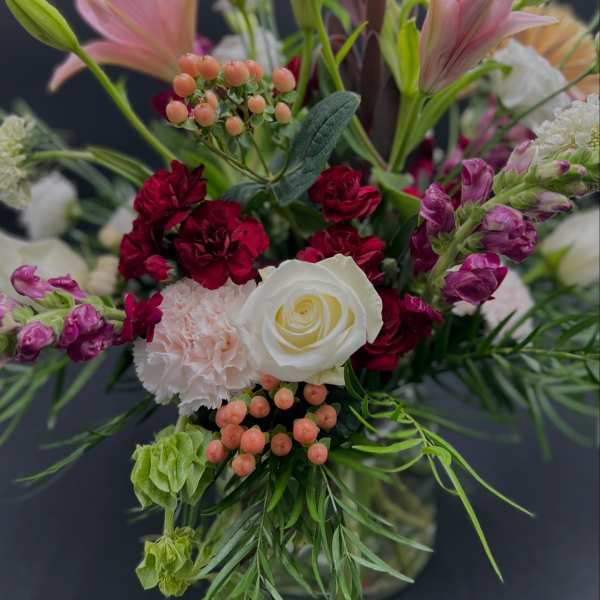 Mixed bouquet with pink lilies, white rose, and red carnations in a vase