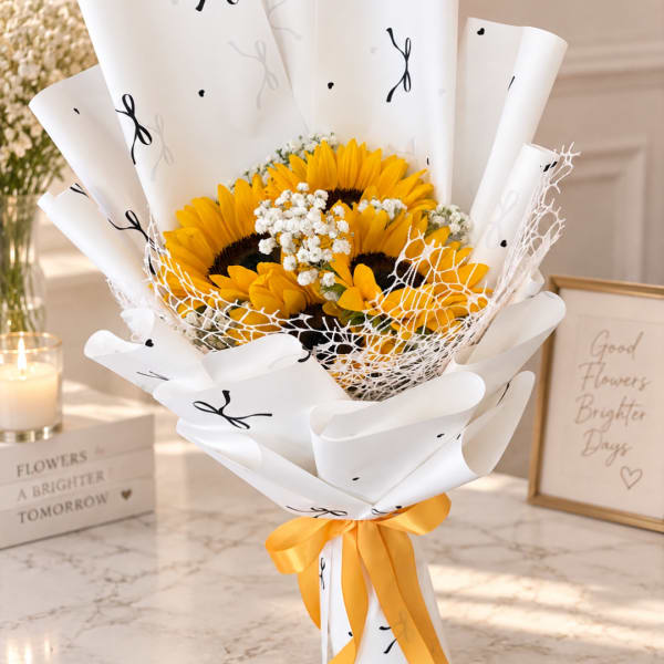 Bouquet of sunflowers wrapped in white paper with a yellow ribbon