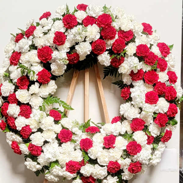 Large red and white carnation wreath on a wooden easel