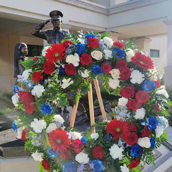 Large patriotic floral wreath on a wooden easel with red, white, and blue flowers