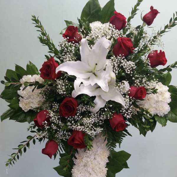 Standing floral cross with red roses, white lilies, and white carnations