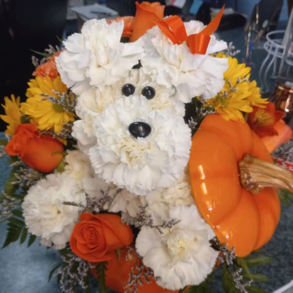 White flower dog arrangement with orange roses and yellow daisies