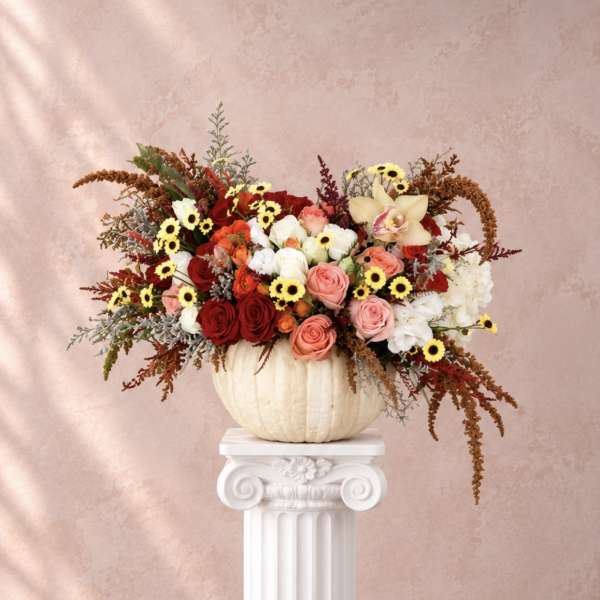 Mixed roses and small daisies arranged in a white pumpkin vase