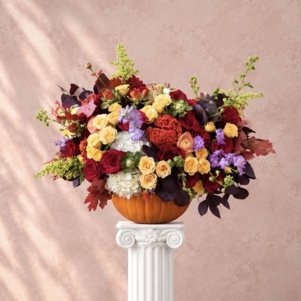 Mixed roses and hydrangeas arranged in a pumpkin vase