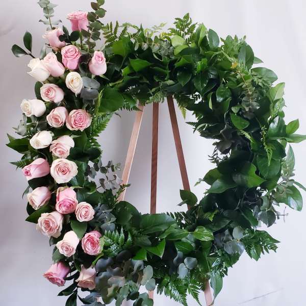 Circular wreath of pink and white roses on a wooden stand