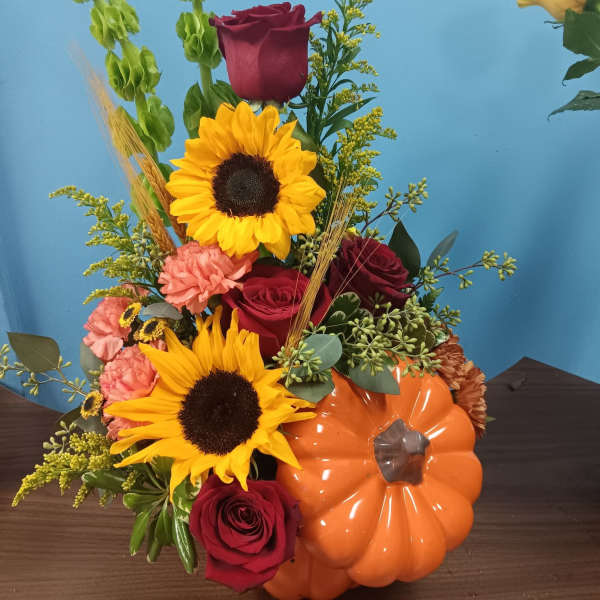 Autumn bouquet with sunflowers, red roses, and a pumpkin container
