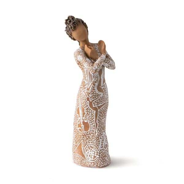 Faceless figurine of a woman in a long brown dress with white decorative patterns, arms crossed over her chest