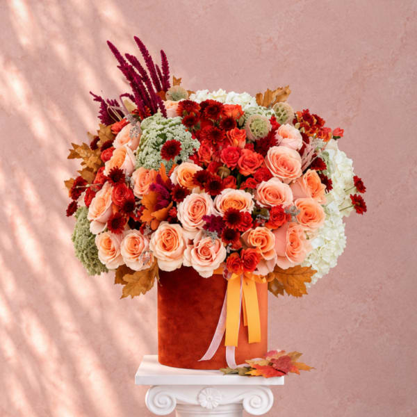 Large bouquet of peach and red roses in a velvet box with ribbons