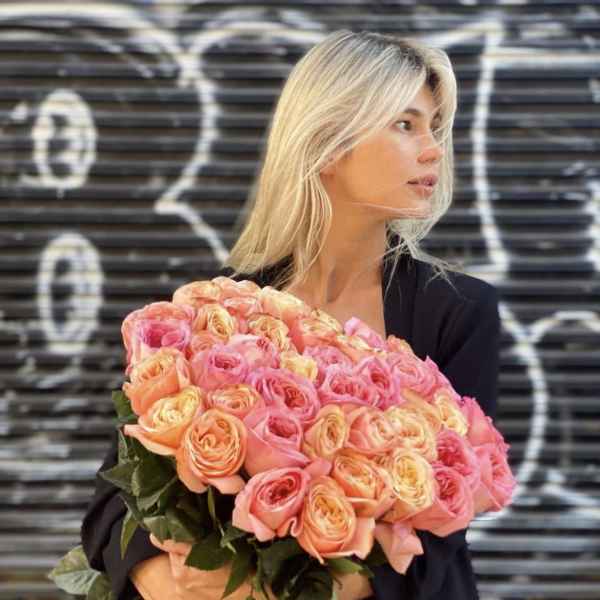Woman holding a large bouquet of pink and peach roses