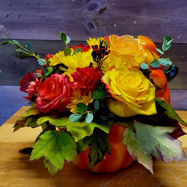Bouquet of yellow and red roses with daisies in a pumpkin container