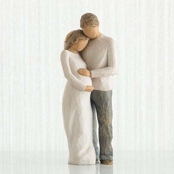 Two carved figurines embracing, one in a white dress and one in gray pants