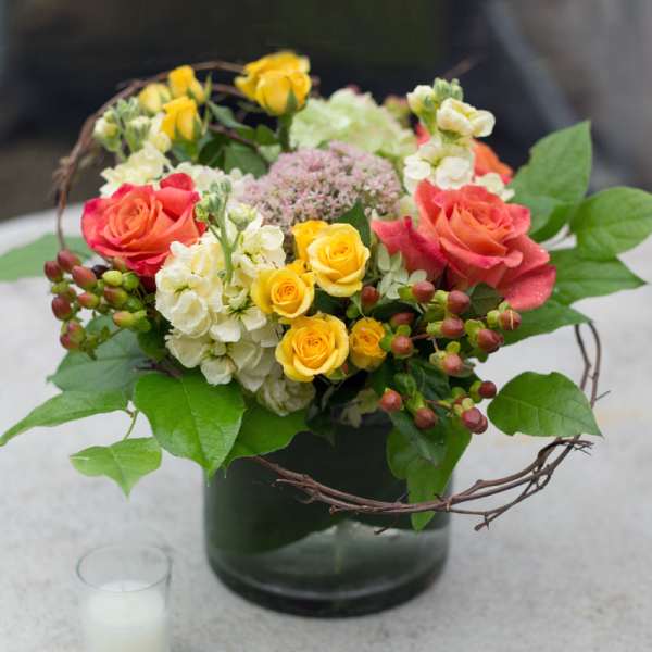 Mixed bouquet of roses and white blooms in a dark glass vase
