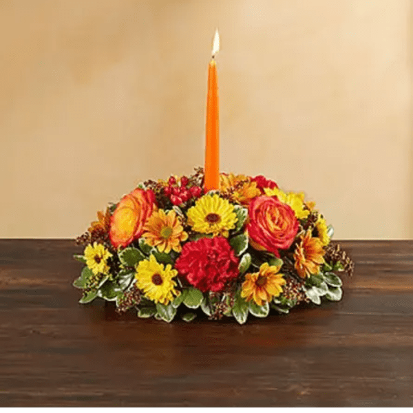 Low floral centerpiece with an orange candle in the middle