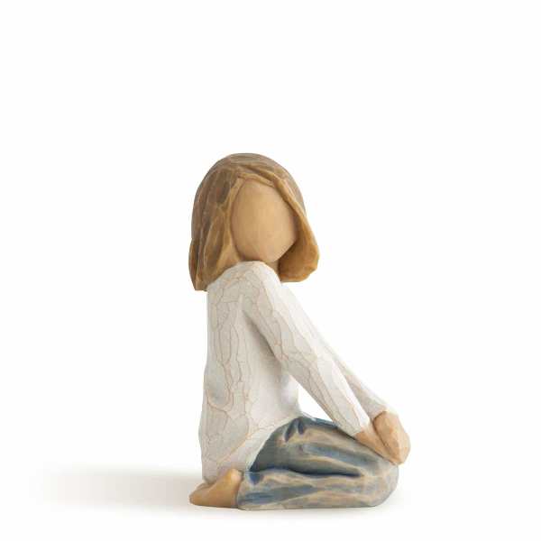 Carved figurine of a seated girl in a white top and blue pants, shown in side profile.