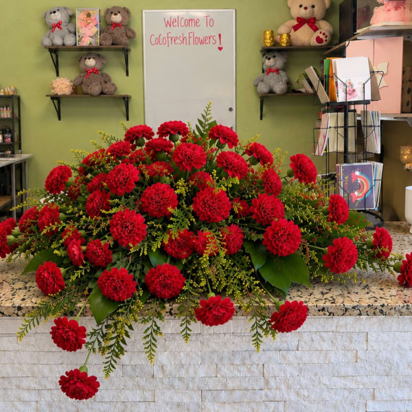 Large red dahlia arrangement on a counter with greenery