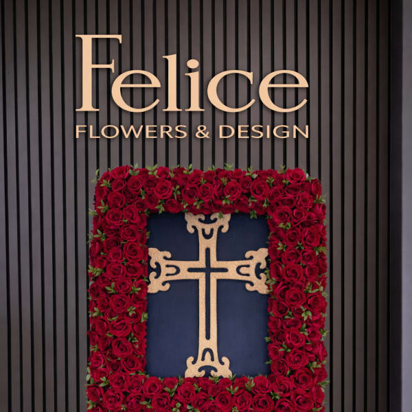 Standing floral cross covered in red roses on an easel