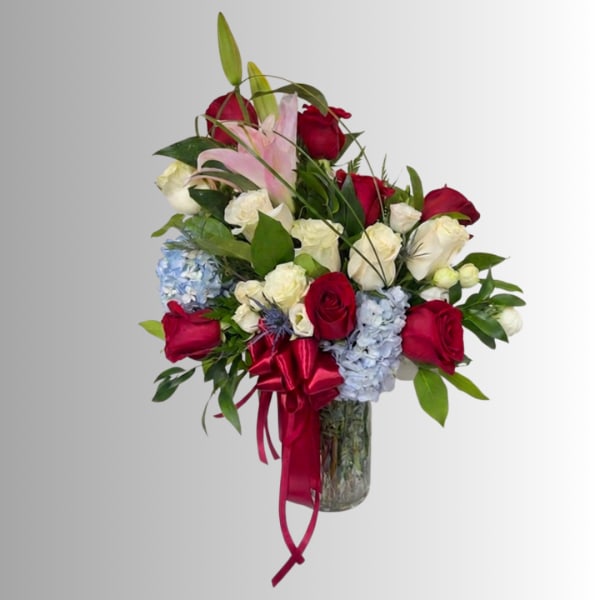 Mixed bouquet of red and white roses with pink lilies in a glass vase