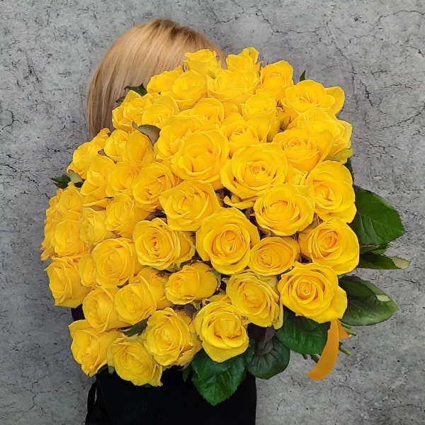 Large bouquet of yellow roses held in front of a person