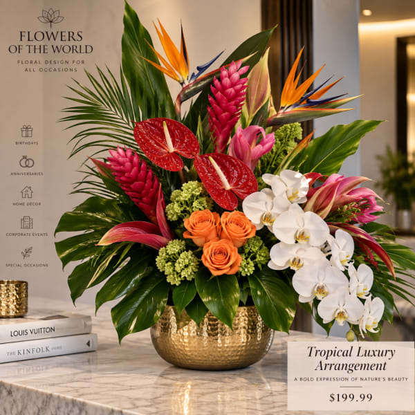 Tropical flower arrangement in a gold vase with orchids, anthuriums, and orange roses