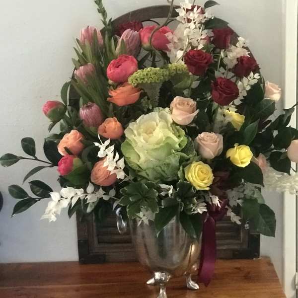 Mixed bouquet of roses, tulips, and orchids in a silver vase