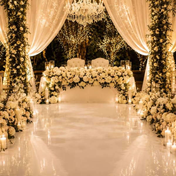 White floral wedding stage with draped fabric and candles