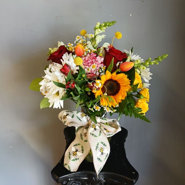 Mixed bouquet with sunflowers, roses, daisies, and tulips in a vase
