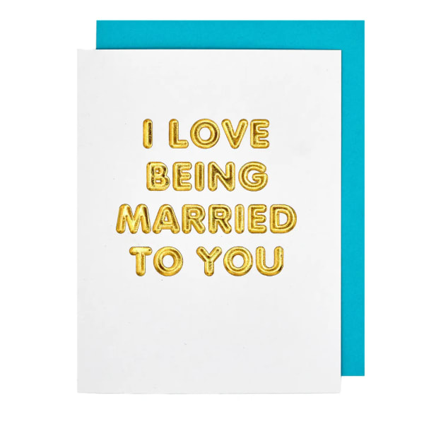White card with gold balloon letters reading I LOVE BEING MARRIED TO YOU