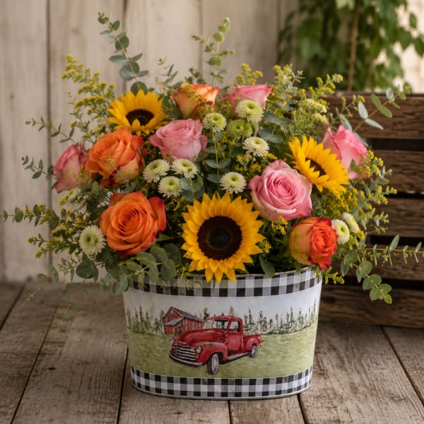 Mixed bouquet of roses and sunflowers in a decorative tin container