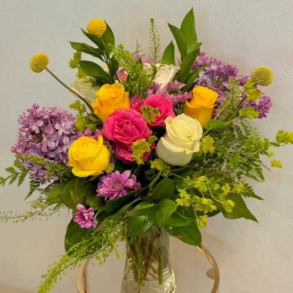 Mixed bouquet of roses and purple flowers in a clear glass vase