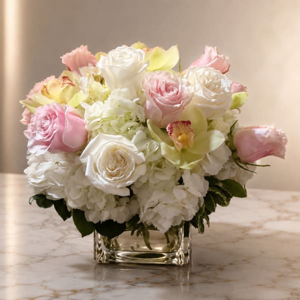 Pink and white roses with orchids in a clear square vase