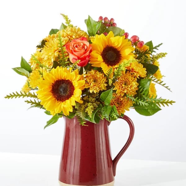 Sunflower and rose bouquet in a red ceramic pitcher