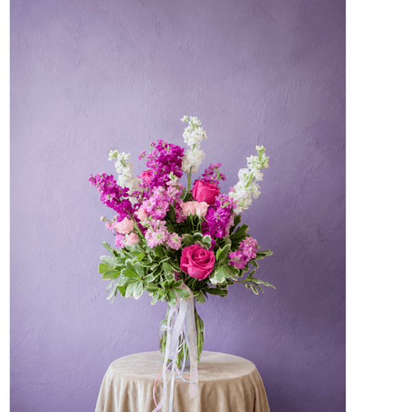 Pink and white flower arrangement in a clear glass vase on a draped table
