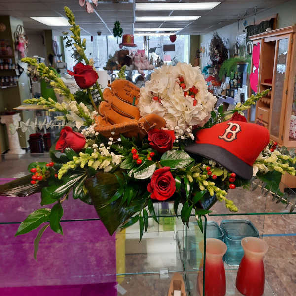 Baseball-themed floral arrangement with red roses and a red cap