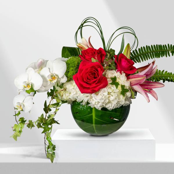 Red roses and white orchids in a green glass vase