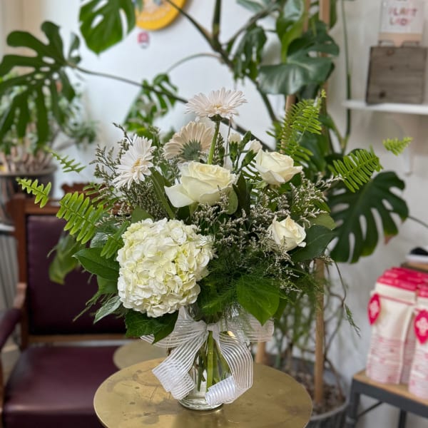 White roses and hydrangea in a glass vase with a ribbon