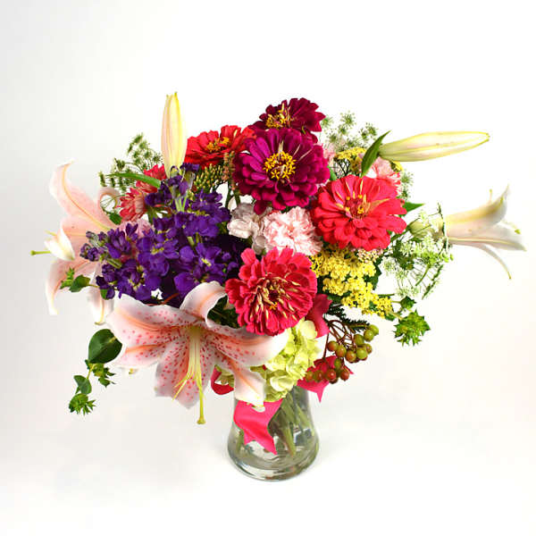 Colorful bouquet of zinnias and lilies in a glass vase