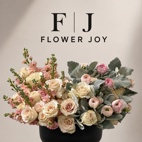 Cream and pink roses with ranunculus in a black pedestal vase