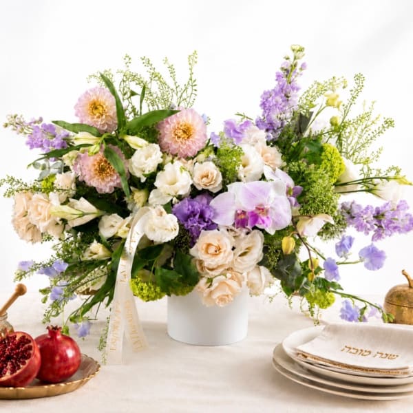 Mixed pastel flower arrangement in a white vase with purple and cream blooms