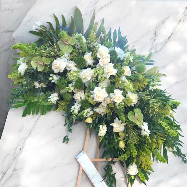 Large white and green floral standing spray on an easel