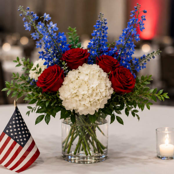 Red roses and white hydrangea in a glass vase with blue flowers
