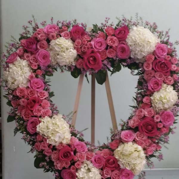 Heart-shaped floral wreath of pink and white roses on an easel