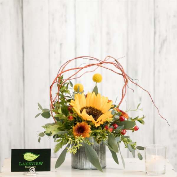 Sunflower arrangement in a metal container with berries and twig accents